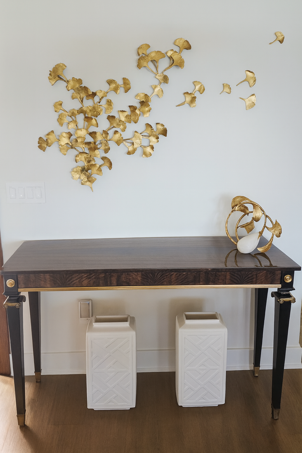 Console table with gold wall sculpture and white stools